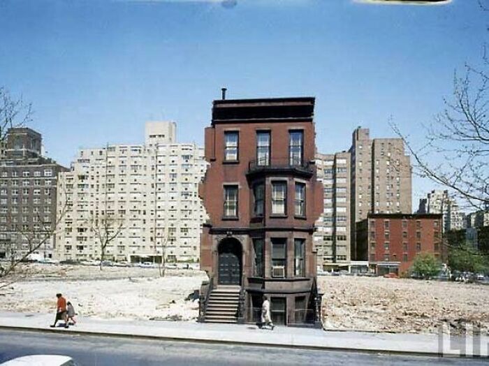 Historic American architecture, solitary brownstone building amidst vacant urban landscape.