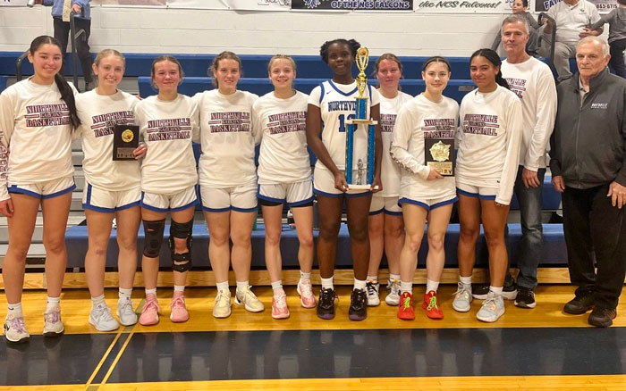 High school basketball team posing with their coach and trophies in a gymnasium. High school basketball team posing with their coach and trophies in a gymnasium.