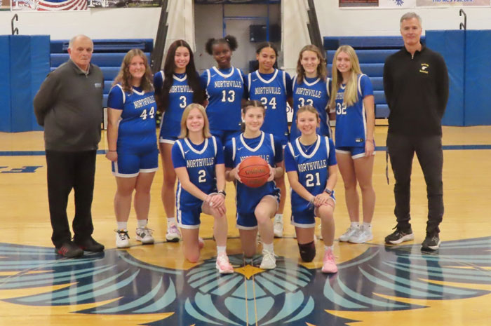 High school basketball team posing on the court with two coaches in an indoor gym. High school basketball team posing on the court with two coaches in an indoor gym.