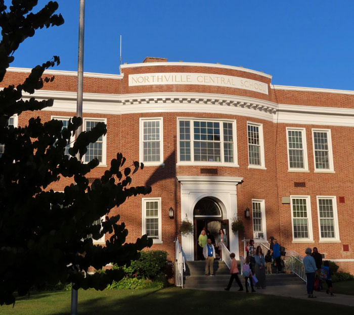 Northville Central School entrance, with people entering and leaving, under a clear sky. Northville Central School entrance, with people entering and leaving, under a clear sky.