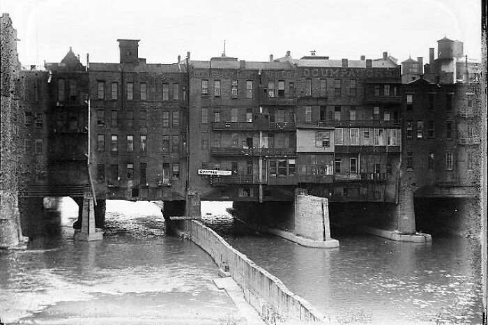 Old American architecture: a historic building spans over a river, showcasing intricate brickwork and structural design.