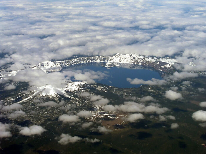 Aerial view of a lake surrounded by snow-capped mountains, illustrating scenic beauty along Legendary American Road Routes.