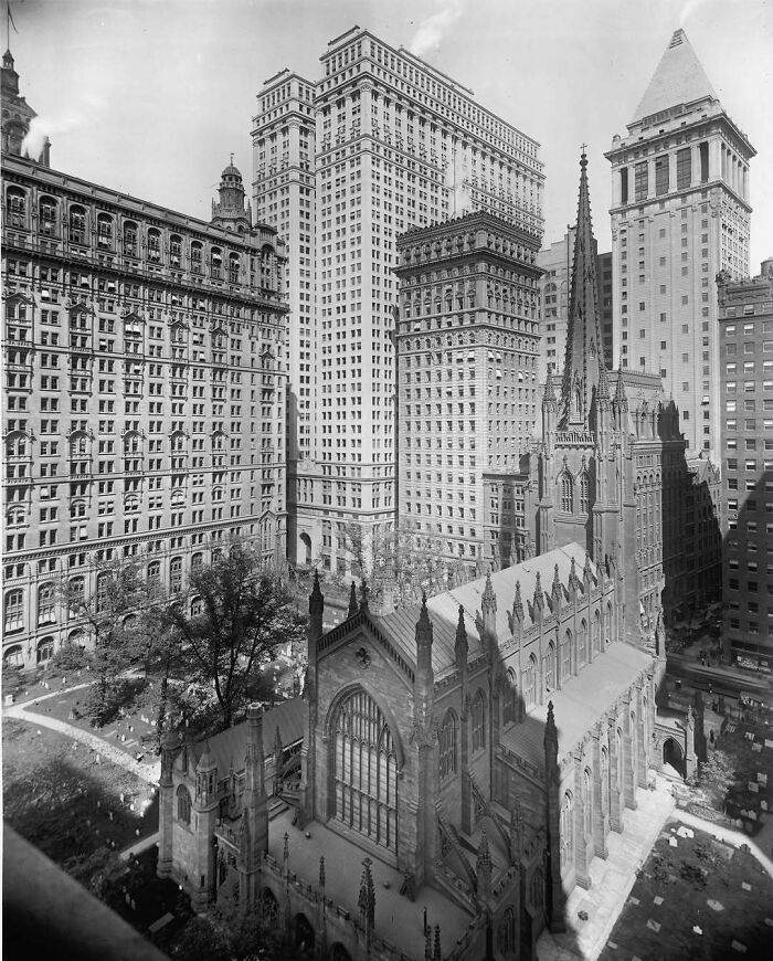 Historic American architecture featuring a Gothic church amid towering skyscrapers in an urban setting.