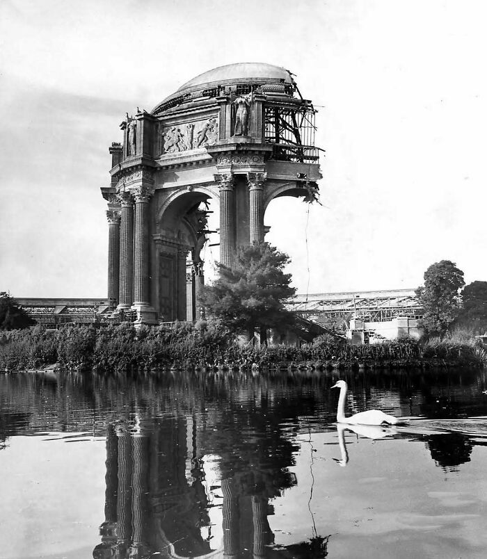 Old American architecture with a swan gliding on a reflective pond.