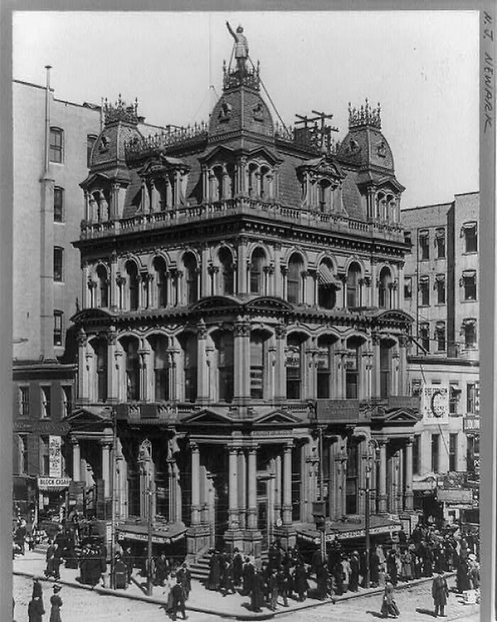 Historic American architecture, ornate building on busy city street, with detailed arches and decorative rooftop features.