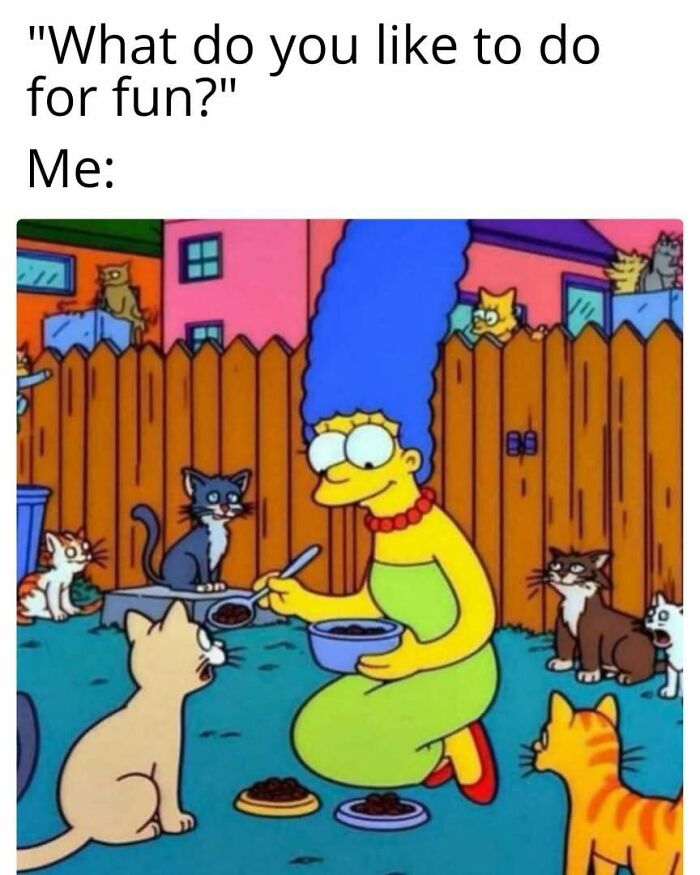 Marge Simpson surrounded by playful cats in a yard, serving them food with a smile.