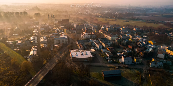 Aerial view of a cityscape at sunrise, with buildings and roads, highlighting the beauty of the city seen from above.