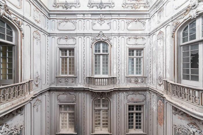 Ornate, vintage architecture of an abandoned building, featuring detailed windows and elegant, aged facade.