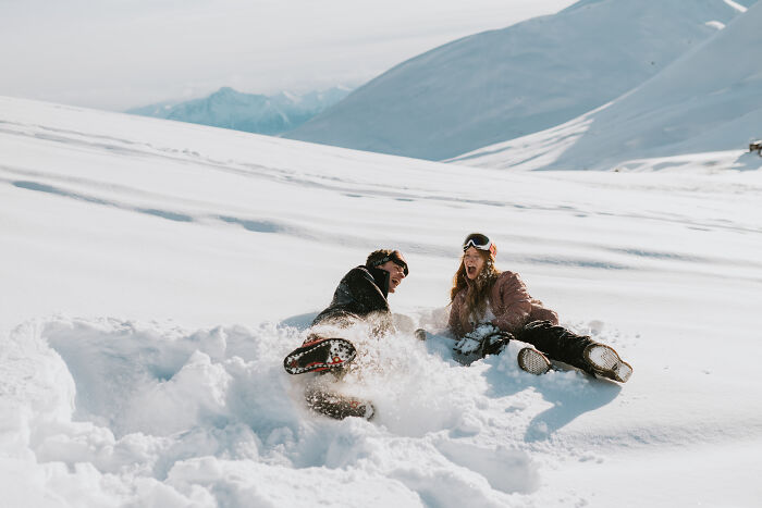 Couple playing in the snow, enjoying a fun winter moment during their engagement photo session in 2025.