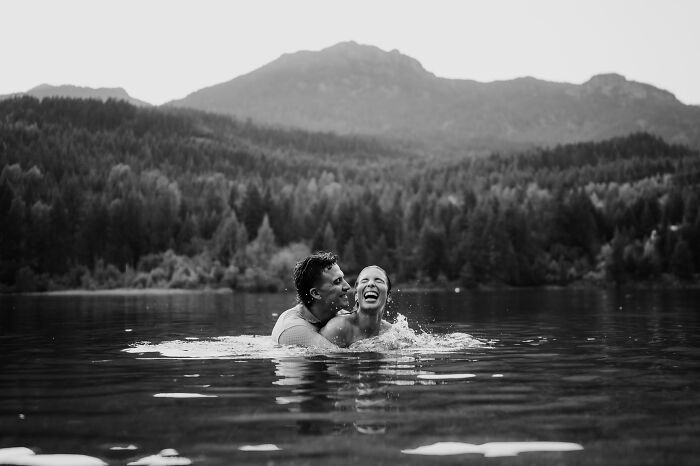 A joyous couple laughing in a lake, with mountains in the background, capturing the essence of top engagement photos 2025.