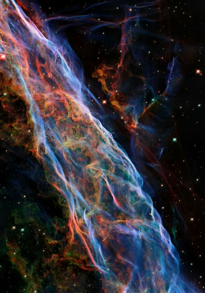 Colorful space nebula with swirling gases and stars, displaying vibrant blues, reds, and oranges against the dark cosmos.