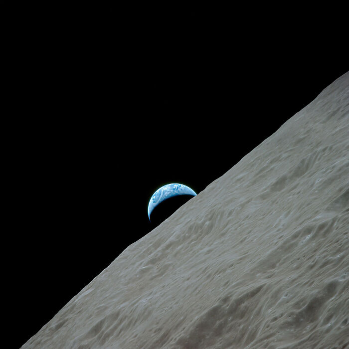Earth rising over the moon's surface, set against the dark void of space. Out of this world space photography.