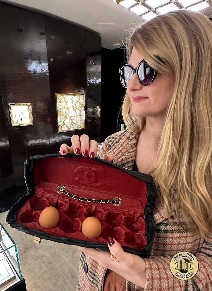 A woman holds a luxury handbag designed for carrying eggs, critiquing high prices. A woman holds a luxury handbag designed for carrying eggs, critiquing high prices.