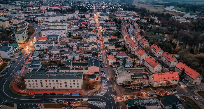 Aerial view of a cityscape with streets, buildings, and lighting at dusk.