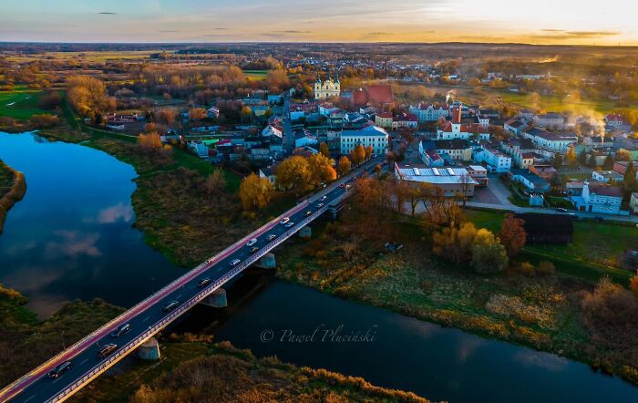 Aerial view of a city with a river and bridge at sunset, showcasing urban landscape seen from above.
