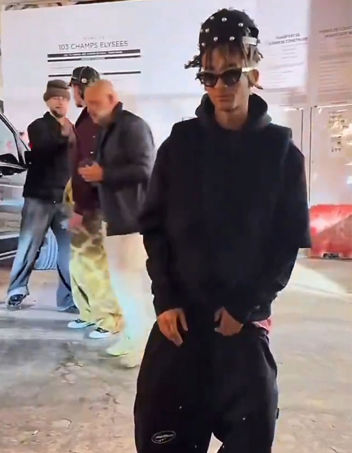 Teen in streetwear with unique hairstyle, standing outdoors, sparking concern with appearance in new video. Teen in streetwear with unique hairstyle, standing outdoors, sparking concern with appearance in new video.