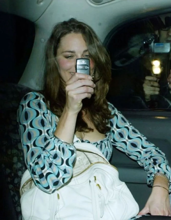 Woman smiling in a car, holding a phone, showcasing stunning pre-princess style with a patterned blouse and white bag. Woman smiling in a car, holding a phone, showcasing stunning pre-princess style with a patterned blouse and white bag.