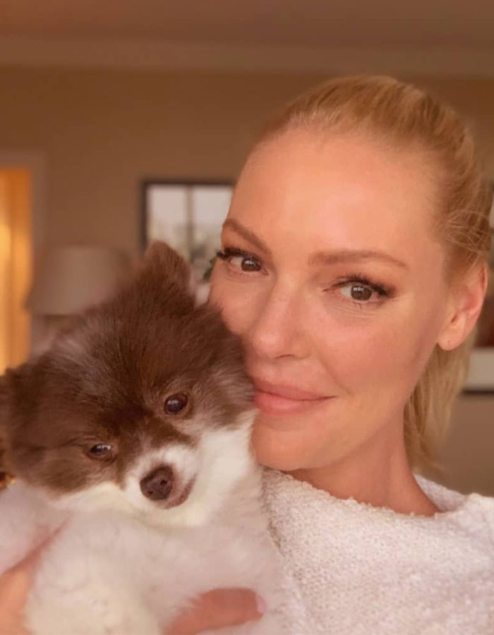 Woman smiling with a small dog, related to a legal issue involving a dog rescue. Woman smiling with a small dog, related to a legal issue involving a dog rescue.