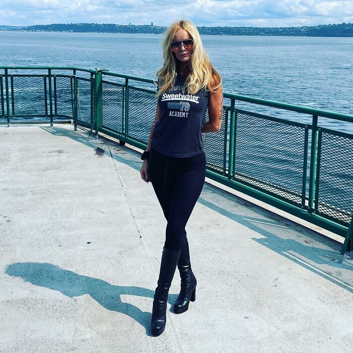 Woman standing on a ship deck with a scenic ocean view, wearing sunglasses and a black outfit. Woman standing on a ship deck with a scenic ocean view, wearing sunglasses and a black outfit.