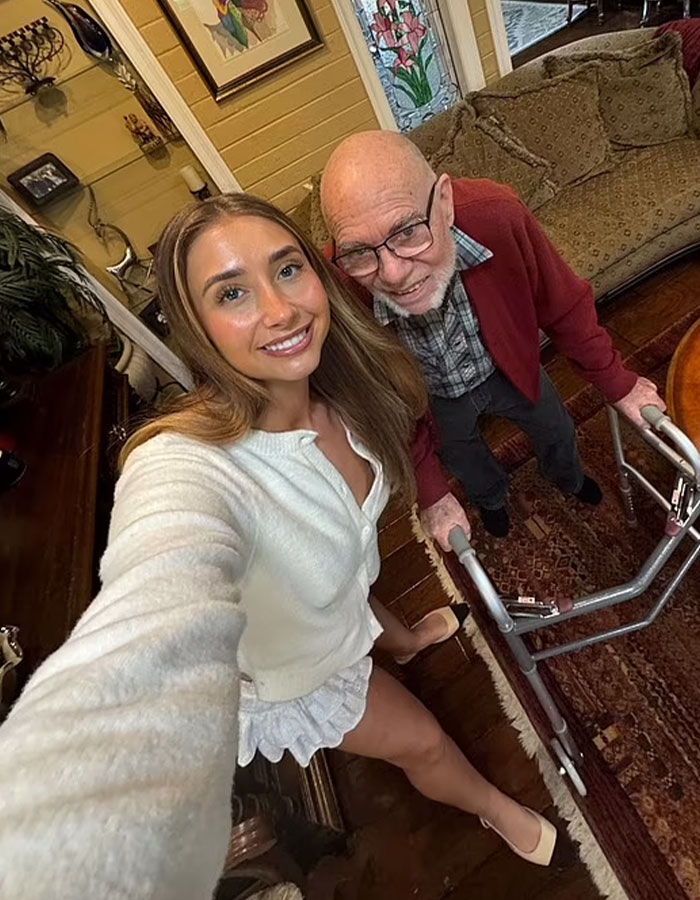 Adult star taking a selfie with an elderly man using a walker in a cozy room. Adult star taking a selfie with an elderly man using a walker in a cozy room.
