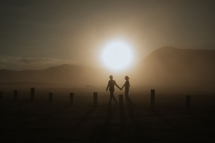 Couple holding hands at sunset, creating a silhouette in one of the best engagement photos of 2025.