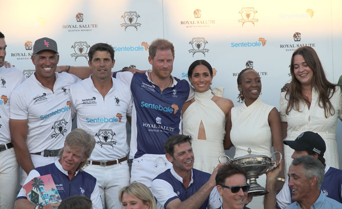 Royal Salute polo event with Harry and Meghan, posing with teammates and a trophy, featuring Sentebale branding. Royal Salute polo event with Harry and Meghan, posing with teammates and a trophy, featuring Sentebale branding.