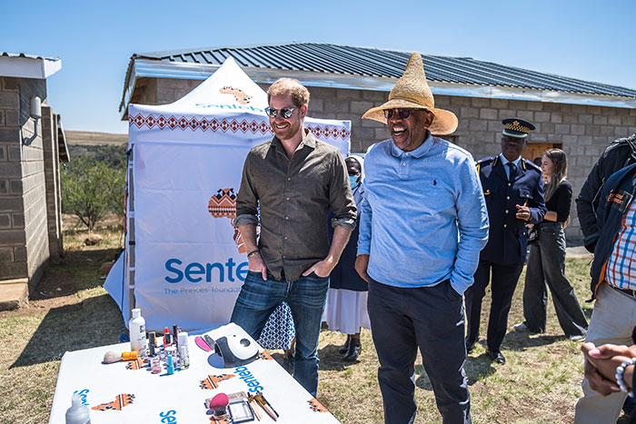Two men smiling at an outdoor charity event with a table of items, highlighting a charity background. Two men smiling at an outdoor charity event with a table of items, highlighting a charity background.