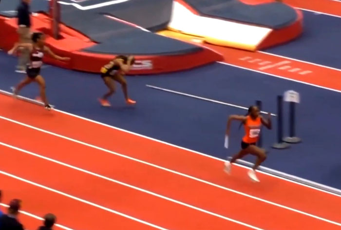 Track star in a relay race, holding a baton, racing on an indoor track. Track star in a relay race, holding a baton, racing on an indoor track.