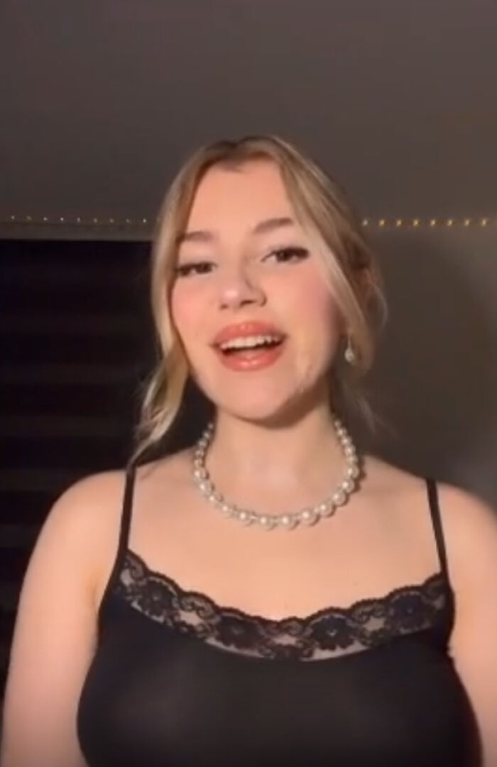 Young woman in a black lace top and pearl necklace, smiling indoors. Young woman in a black lace top and pearl necklace, smiling indoors.