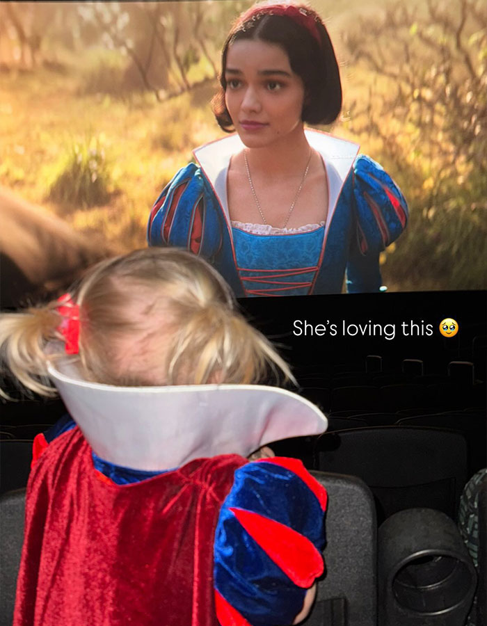 Child in a Snow White costume watching Disney's new Snow White film in a theater. Child in a Snow White costume watching Disney's new Snow White film in a theater.