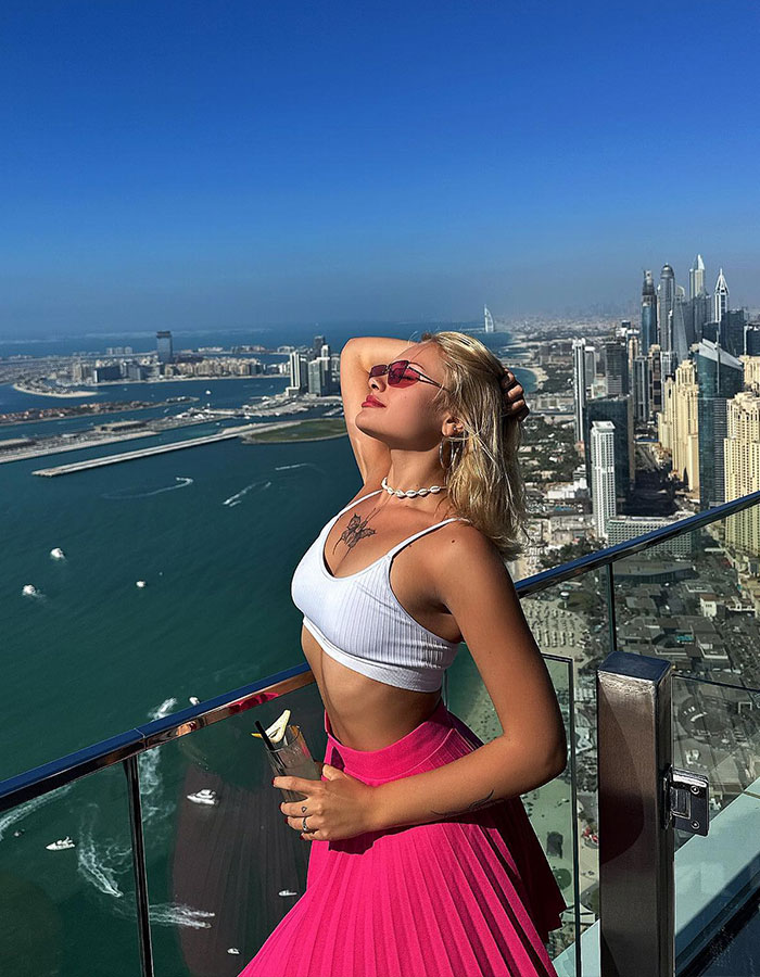 Model in vibrant outfit posing on a high-rise balcony overlooking a vast cityscape. Model in vibrant outfit posing on a high-rise balcony overlooking a vast cityscape.
