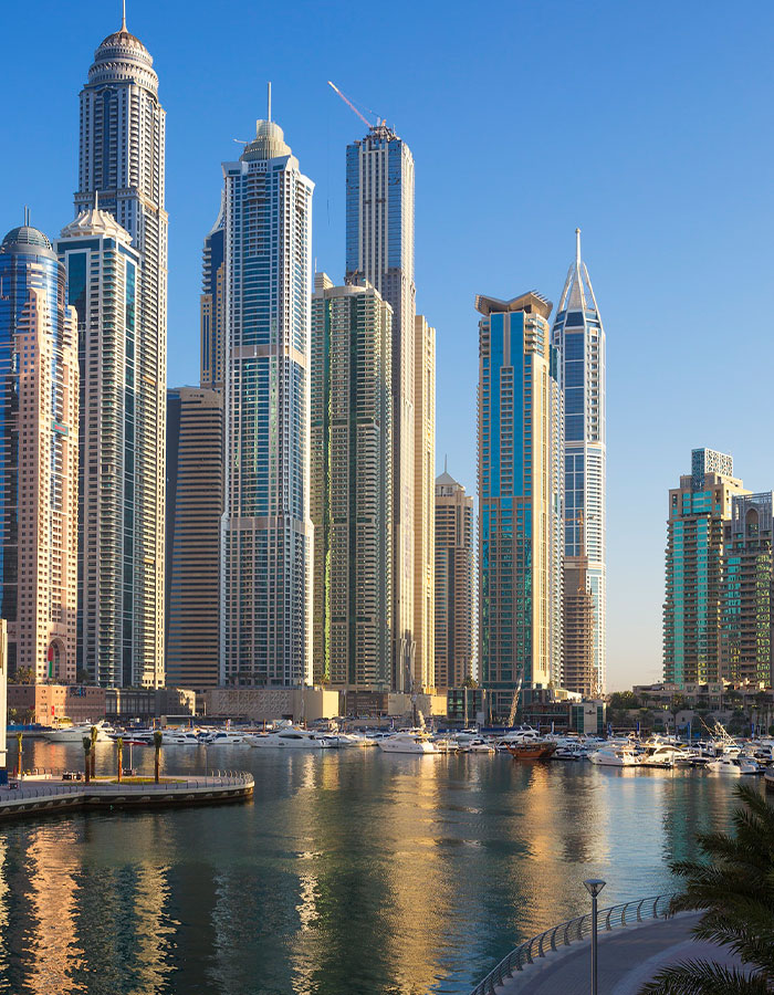 Skyscrapers by marina in Dubai under blue sky, reflecting on water. Skyscrapers by marina in Dubai under blue sky, reflecting on water.