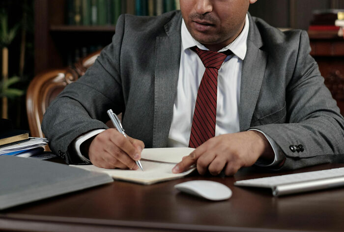 Man in a suit writing at a desk, challenging job misconceptions.