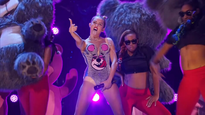 Performer in a playful outfit and sunglasses dancers create a scandalous moment on stage at an awards show.