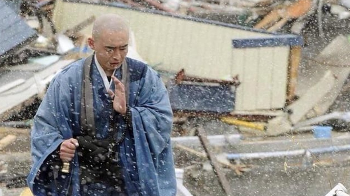 A monk in blue robes walking through snowfall amid debris, captured in a striking accidental Renaissance photo.
