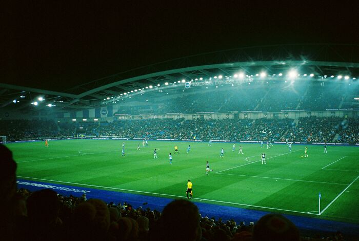 Soccer match in a large illuminated stadium packed with fans, one of the iconic cathedrals of soccer where legends are born.