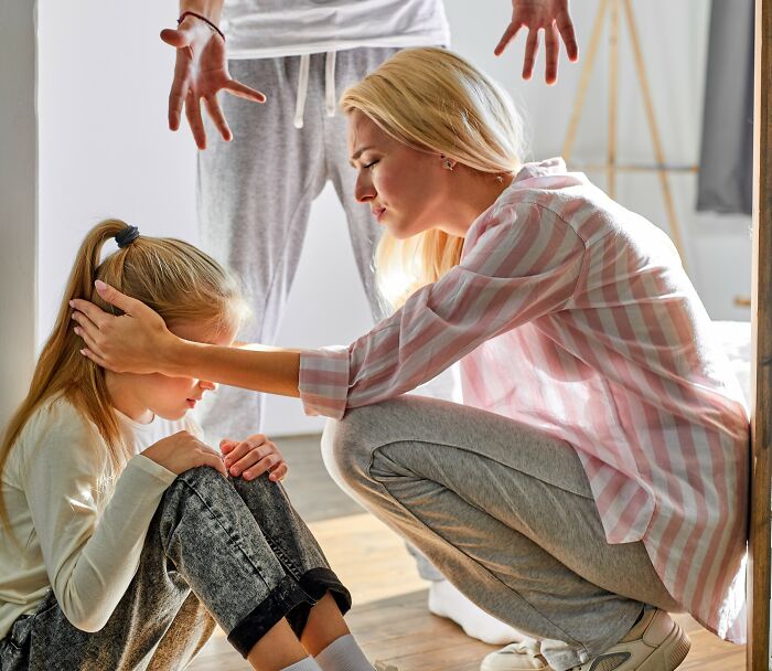 A woman comforts a child on the floor while an adult gestures nearby, depicting an insignificant thing stuck forever.