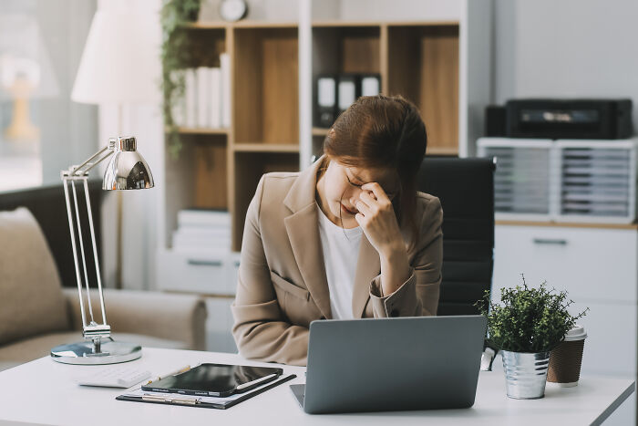 A woman at a desk appears stressed, illustrating misunderstood 'healthy' habits.
