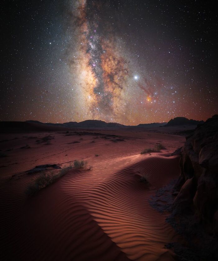 Milky Way galaxy over a desert landscape, showcasing stunning space imagery and starry night sky.