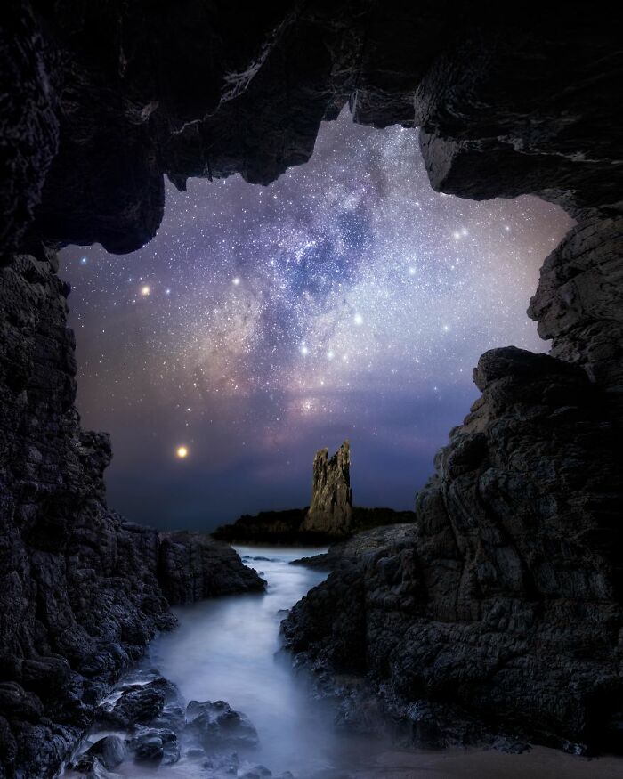 Starry night sky with the Milky Way seen from a rocky cave, depicting stunning space views.
