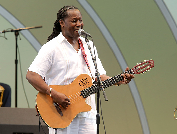 Popular singer performing with a guitar on stage in a white outfit. Popular singer performing with a guitar on stage in a white outfit.