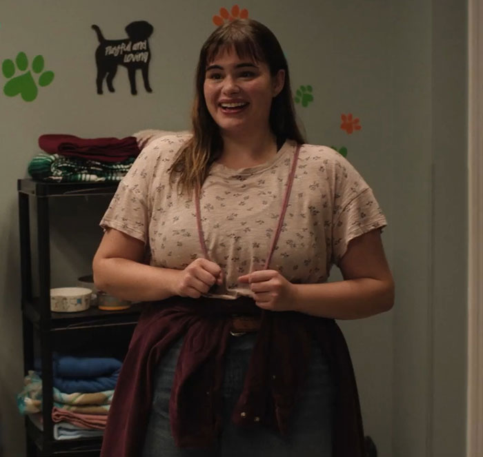 Barbie Ferreira in a movie scene before weight loss, wearing a casual outfit with dog-themed wall decor. Barbie Ferreira in a movie scene before weight loss, wearing a casual outfit with dog-themed wall decor.