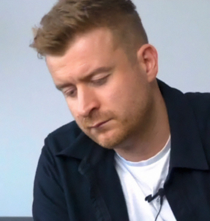 Man in casual attire looking down, symbolizing a work-related issue during vacation. Man in casual attire looking down, symbolizing a work-related issue during vacation.