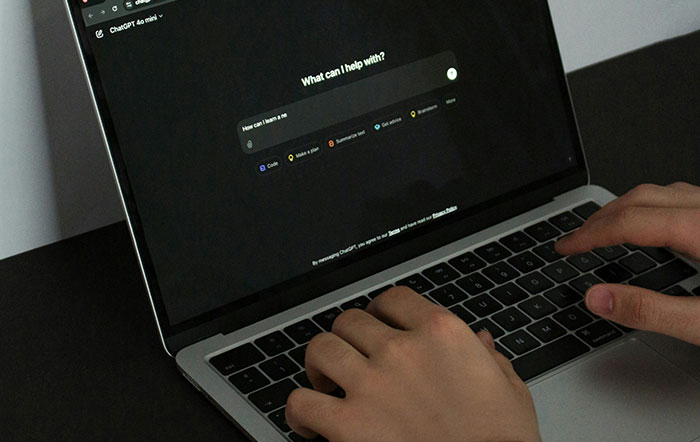 Hands typing on a laptop showing AI interface, highlighting environmental concerns. Hands typing on a laptop showing AI interface, highlighting environmental concerns.