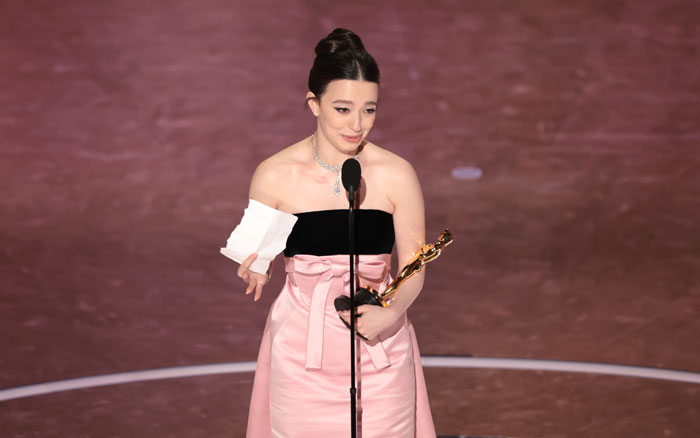 Recipient holding Oscar statuette during the 2025 Oscars ceremony, dressed in a pink and black gown on stage. Recipient holding Oscar statuette during the 2025 Oscars ceremony, dressed in a pink and black gown on stage.