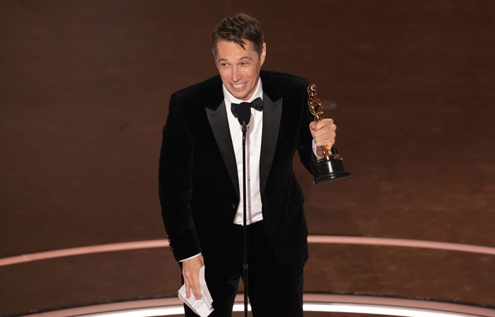 Winner at Oscars 2025 holding an award in a black tuxedo, smiling on stage. Winner at Oscars 2025 holding an award in a black tuxedo, smiling on stage.