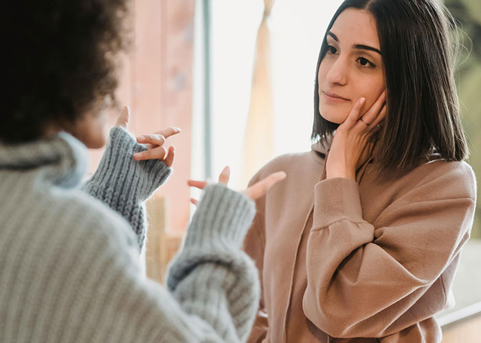 Two women having a serious conversation about a wedding and bridesmaid duties in a cozy setting. Two women having a serious conversation about a wedding and bridesmaid duties in a cozy setting.