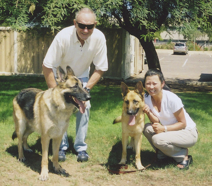 Two people with German Shepherds in a sunny park, linked to Gene Hackman mystery news. Two people with German Shepherds in a sunny park, linked to Gene Hackman mystery news.
