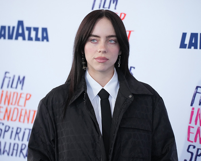 Billie Eilish look-alike in a black jacket and tie at a public event, causing mall chaos despite differing opinions. Billie Eilish look-alike in a black jacket and tie at a public event, causing mall chaos despite differing opinions.