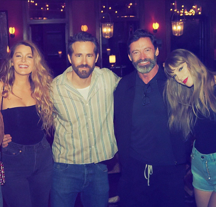 Four people posing closely together in a warmly lit room, featuring Hugh Jackman. Four people posing closely together in a warmly lit room, featuring Hugh Jackman.